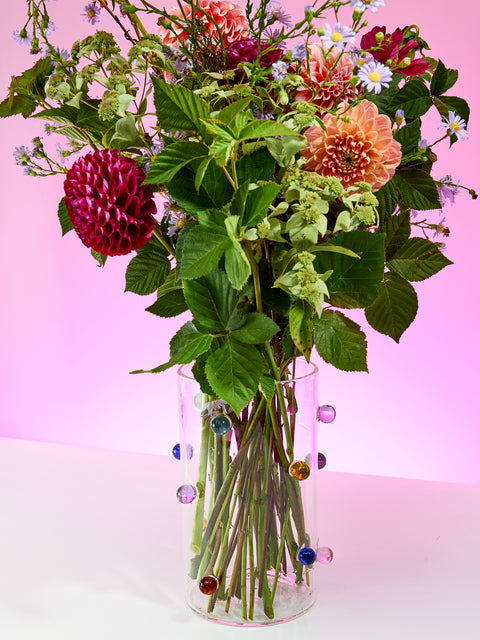 Dot Vase full of flowers on a purple background.