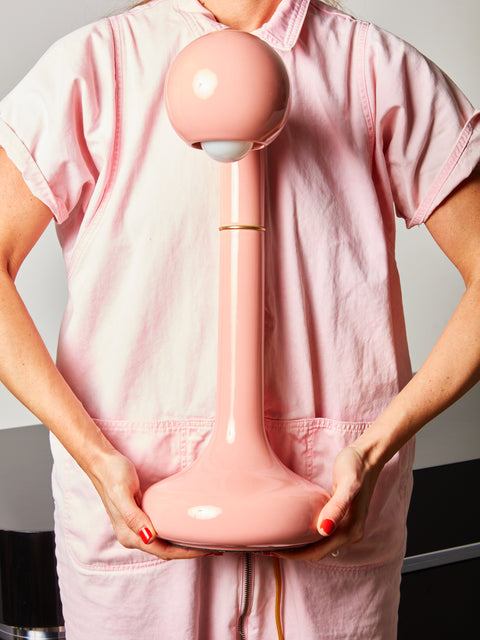 Someone holding a Pink ceramic table lamp by Entler Studio.