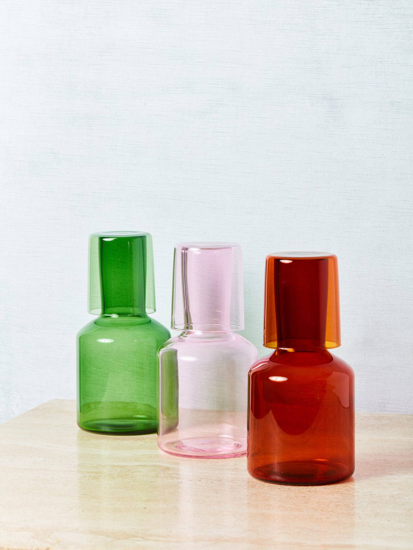 A green, pink, and amber bedside carafe by maison balzac.