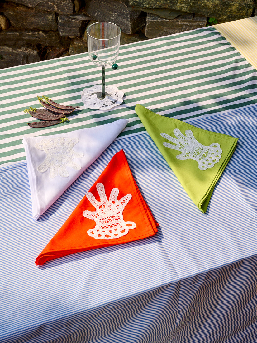 Three dinner napkins folded into triangles with a lace appliqué hand adorned on the corner of each napkin.