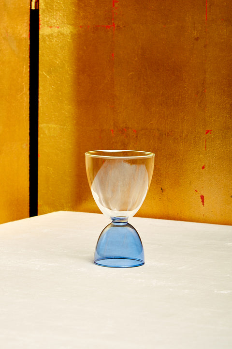A clear top blue bottom cocktail glass.
