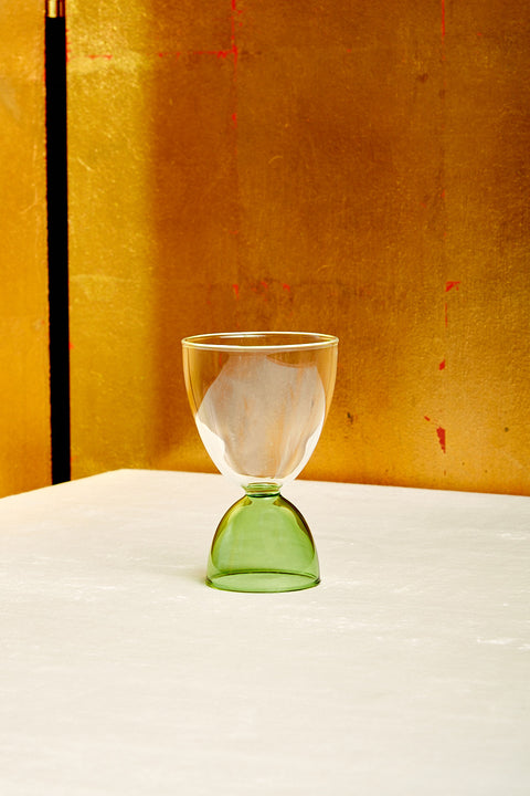 A clear top green bottom cocktail glass.