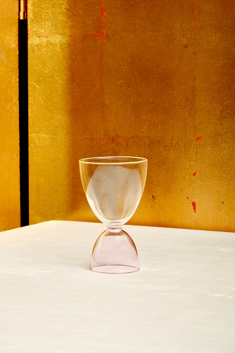 A clear top pink bottom cocktail glass.