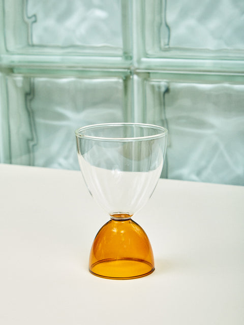 A clear top amber bottom cocktail glass.