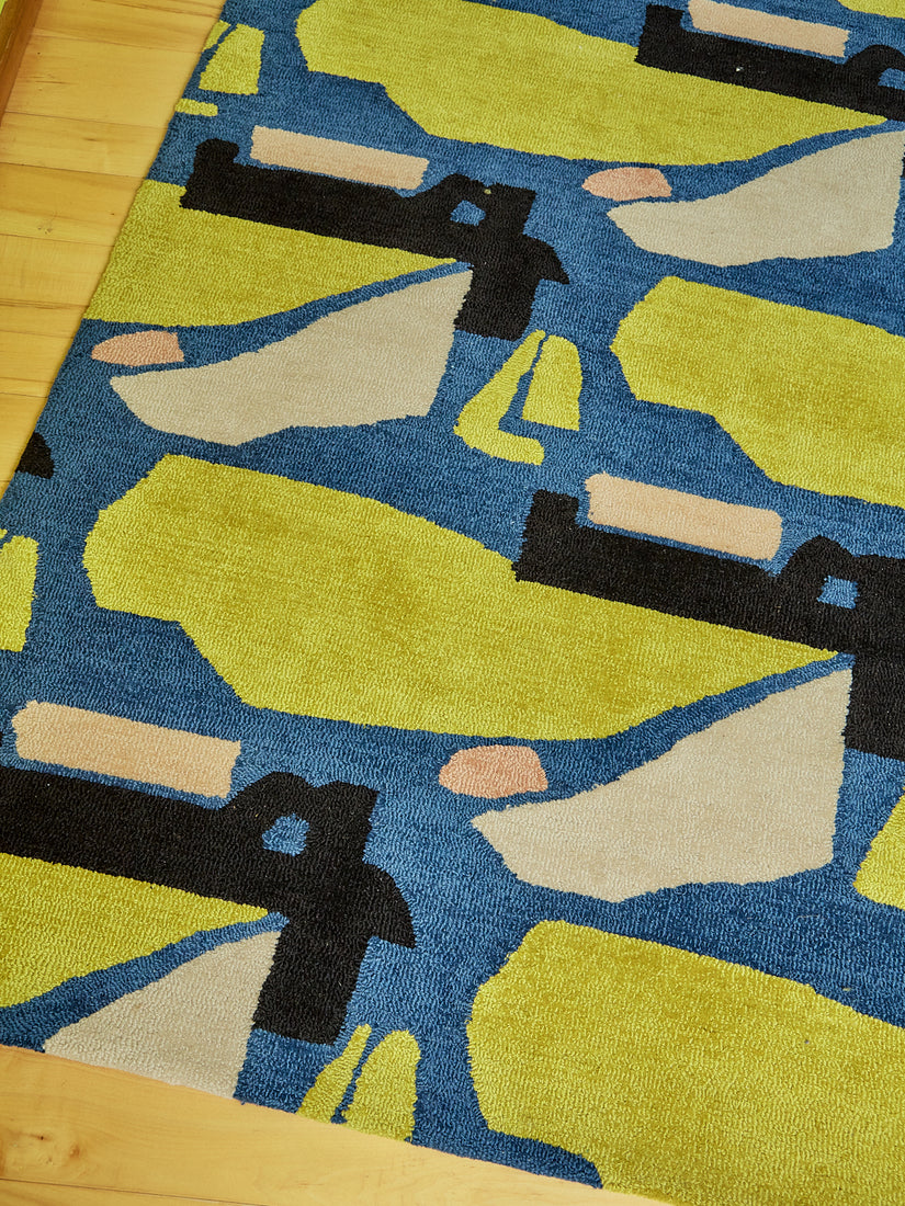 Close up of the mostly royal blue rug with abstract forms of chartreuse, black, cream, and peach.