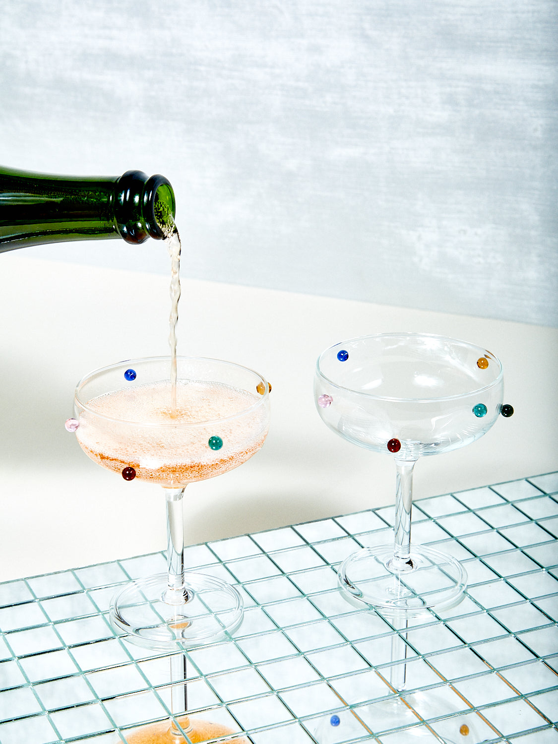 A bottle of champagne being poured into one of two Dot Coupes.