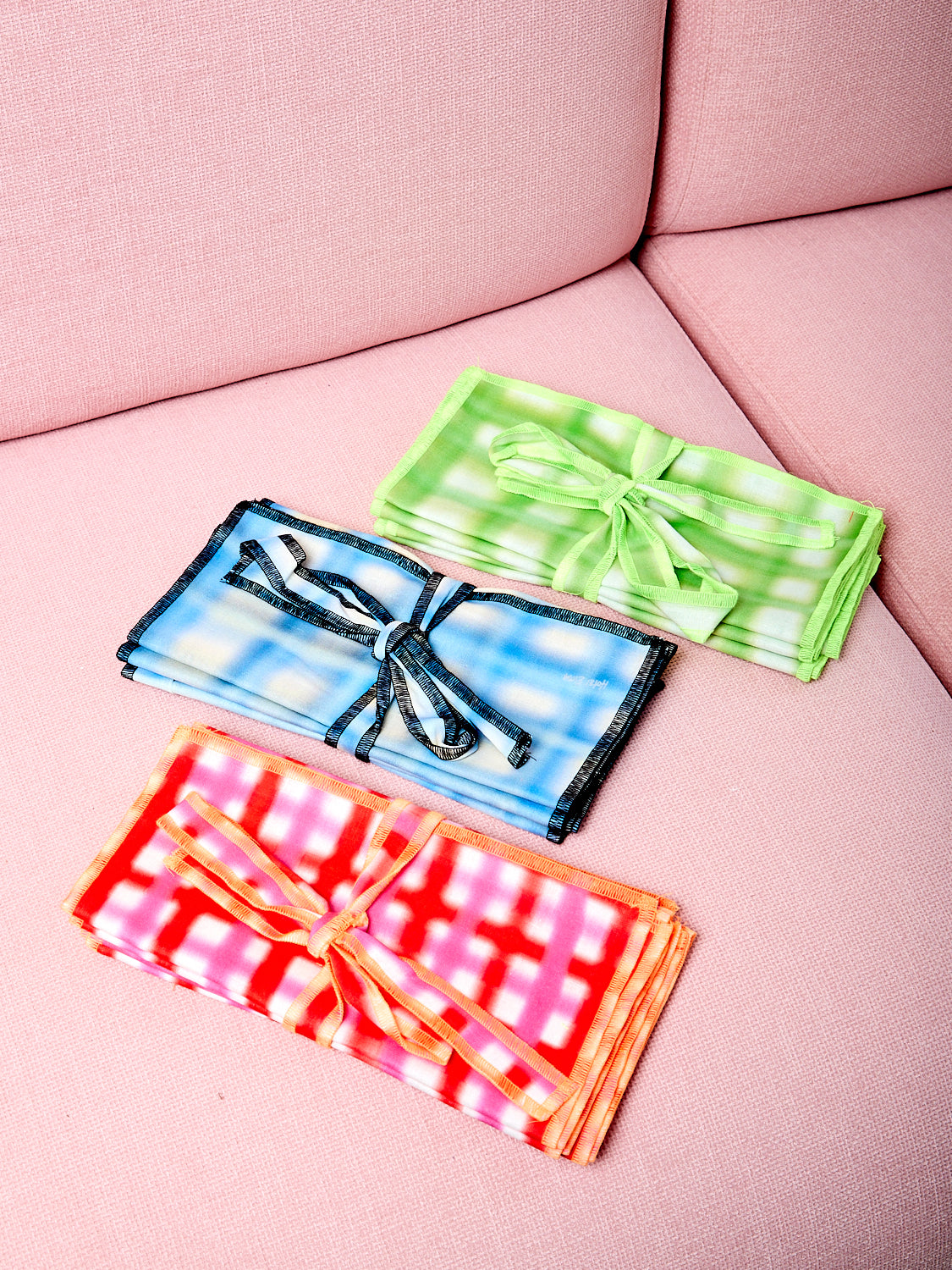 Three colorways of airbrushed napkins on a pink chair.