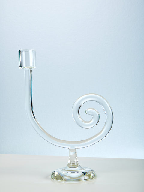 Clear glass candle holder with spiral design on a light blue background