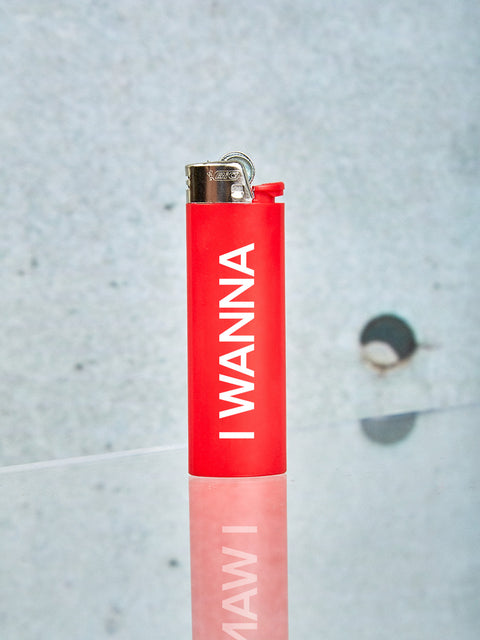 A red Bic Lighter with the words I WANNA in white printed on it.
