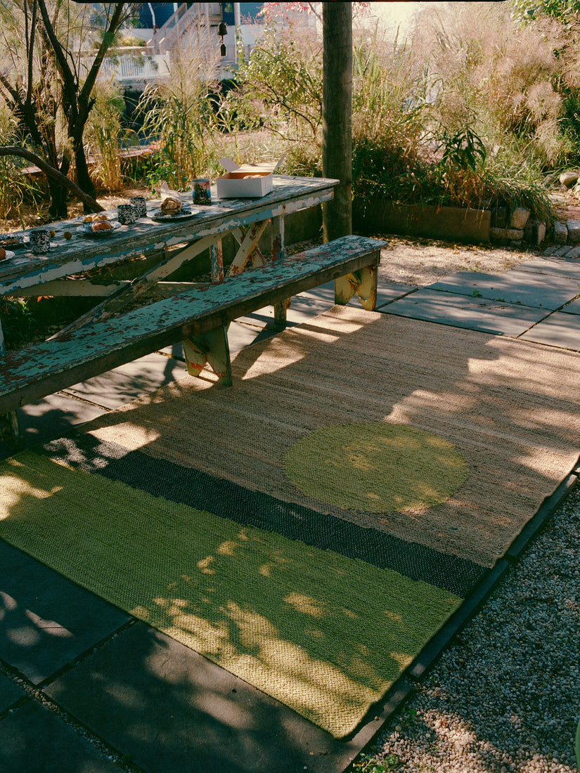 The Changeling Rug by Cold Picnic featured in an outdoor garden.