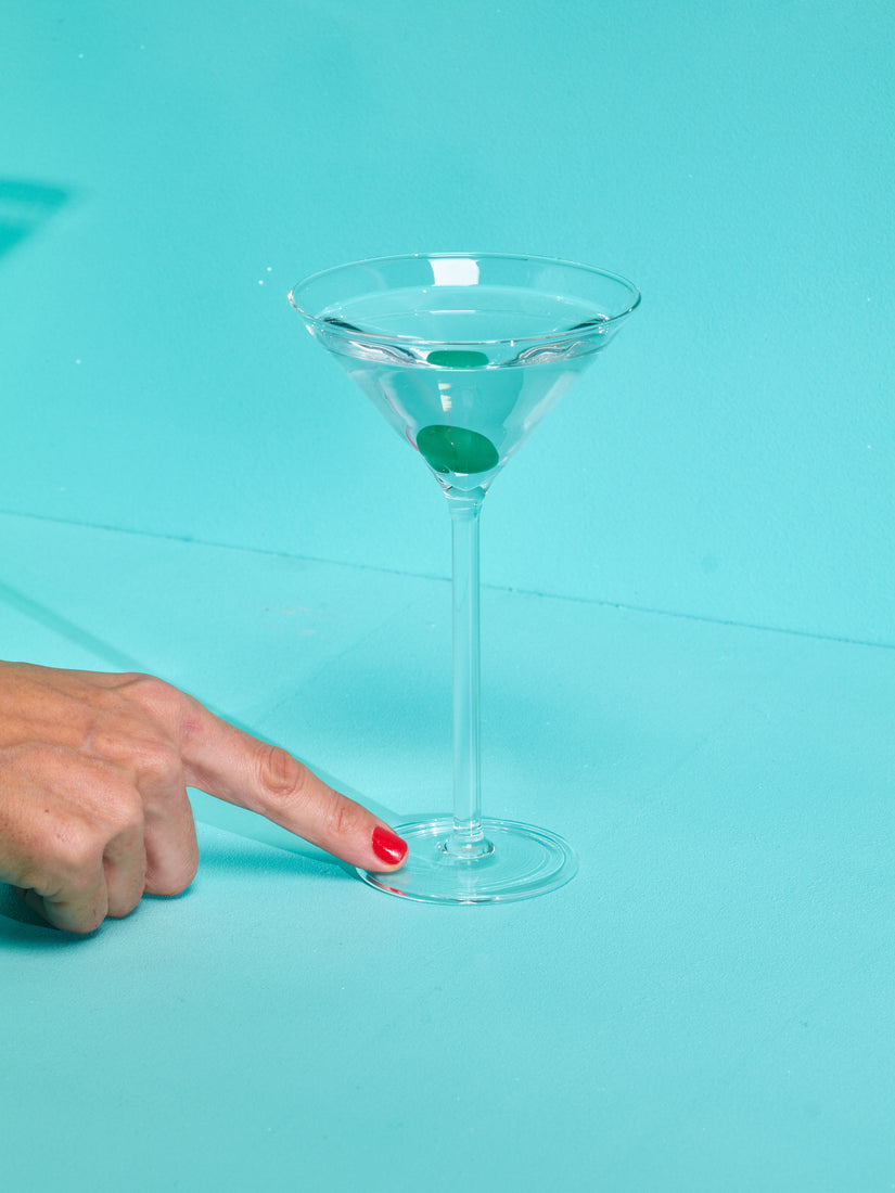 A finger points at the base of a Martini Glass by Maison Balzac.