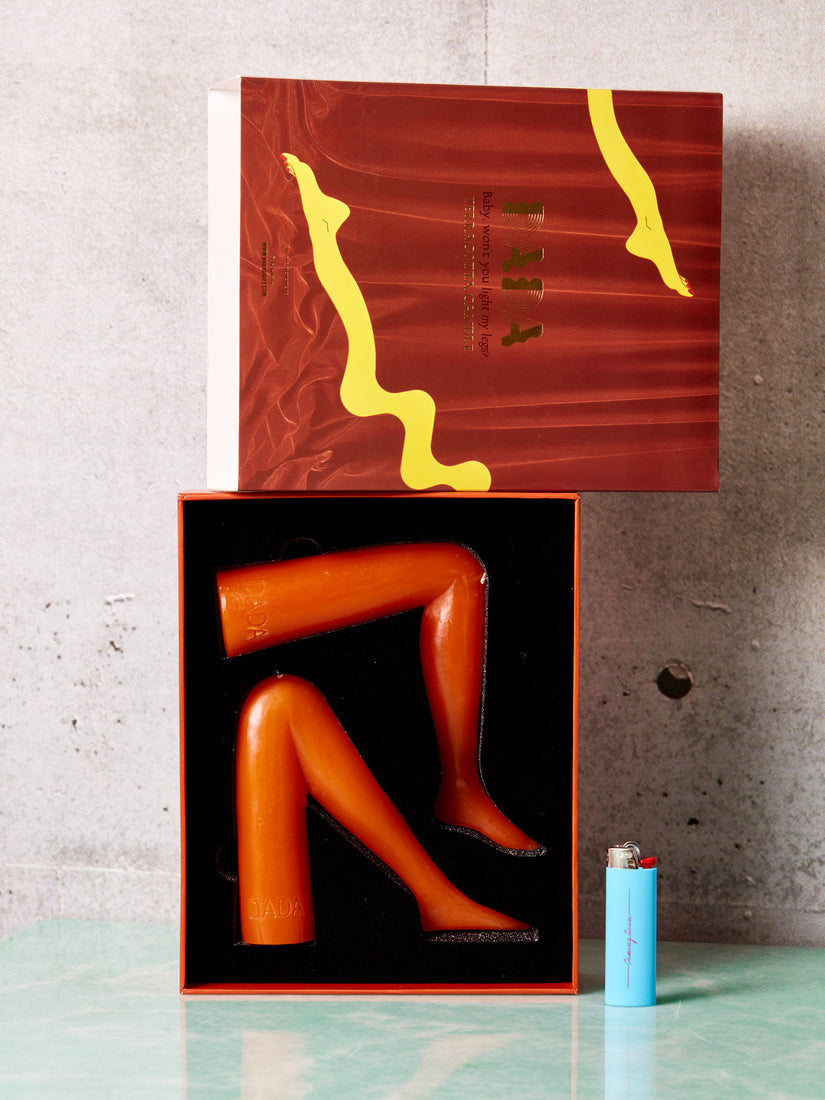 Orange leg shaped candles by Dada displayed open with a blue Coming Soon lighter placed next to it.