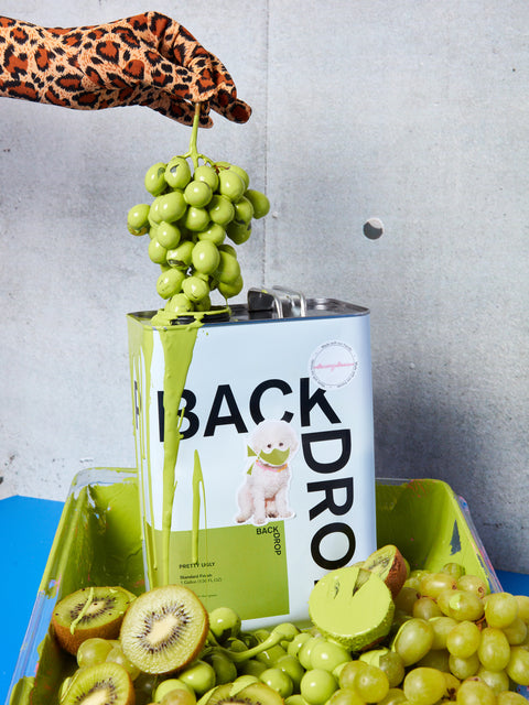 A hand holds green grapes above a can of "Pretty Ugly" green paint.