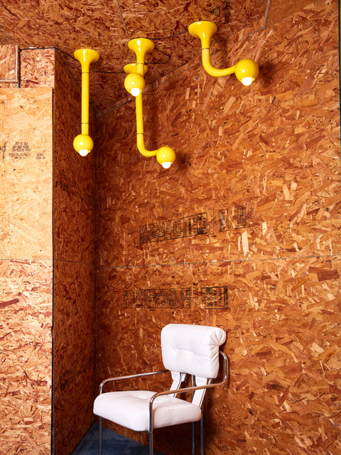 Four ceramic ceiling lamps by Entler Studio in a plywood room above a pink chair.