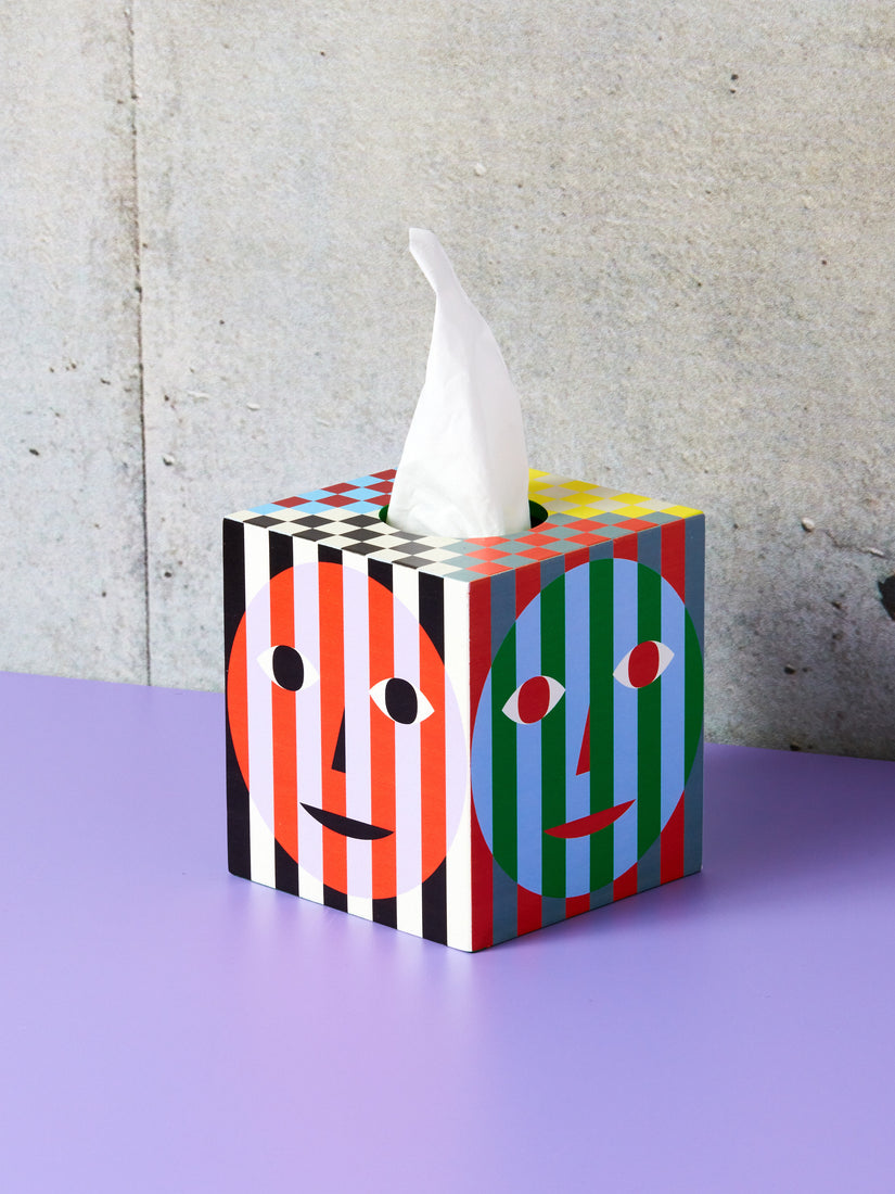 Tissue Box Holder by Dusen Dusen for Areaware sitting on a lilac surface with a tissue pulled up and out of its hole.