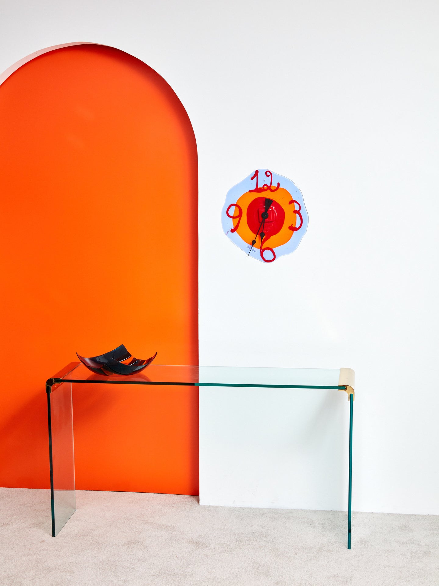 Handmade resin Watch Me Clock hung on a white wall above a glass console table.