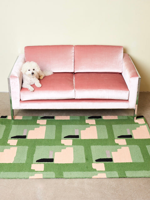 A pink velvet couch on top of a Purple Noon rug by Cold Picnic.