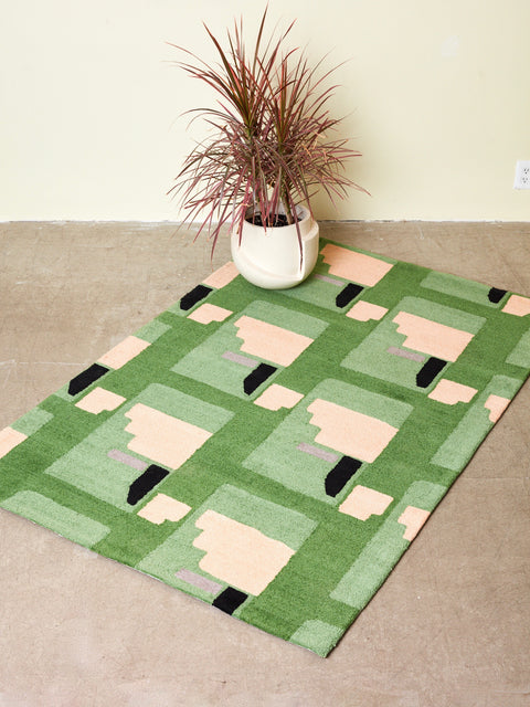 A palm plant on the corner of a Purple Noon rug by Cold Picnic.
