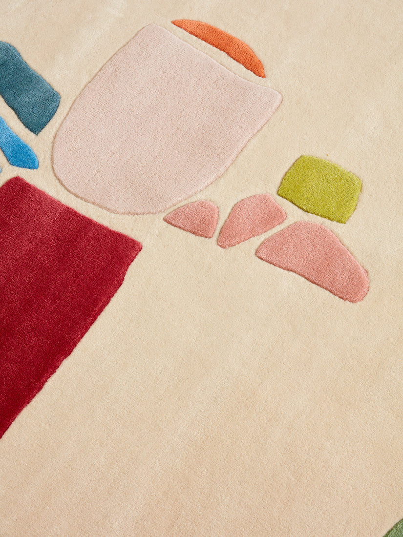 Close up of the From the Ferry Rug showing its mostly cream base with high pile abstract forms of red, blue, peach, pink, orange, and green.