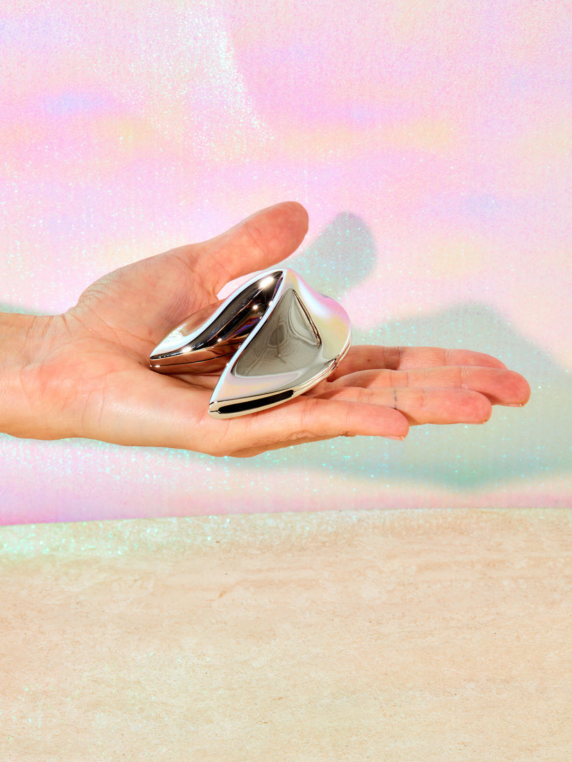 A hand holding the chrome fortune cookie.