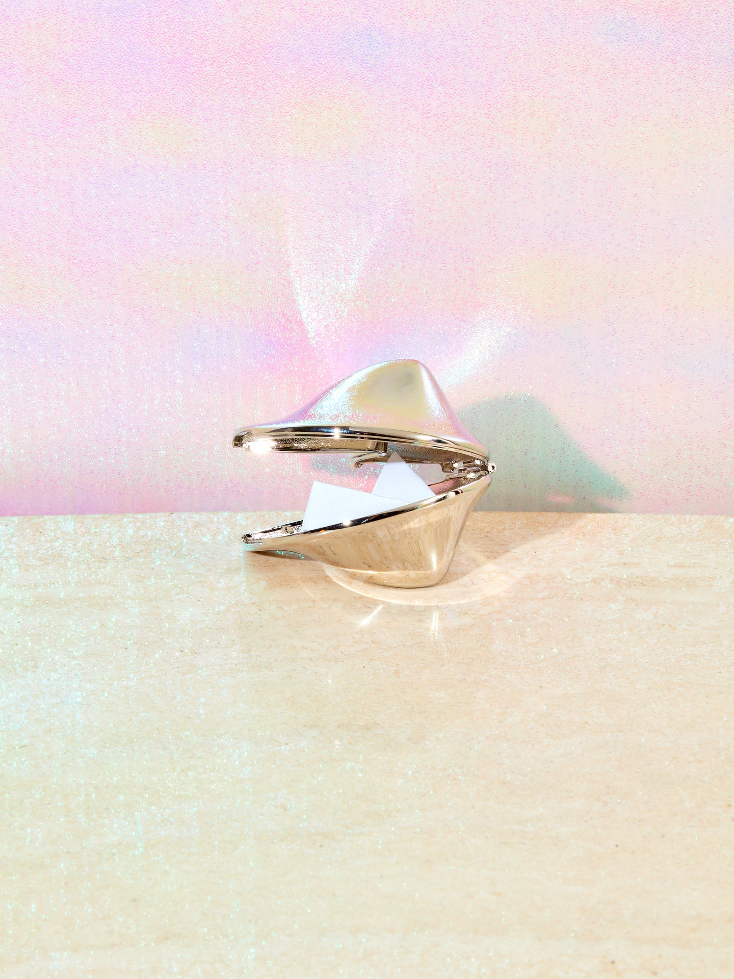 Chrome fortune cookie ajar showing its paper inside.
