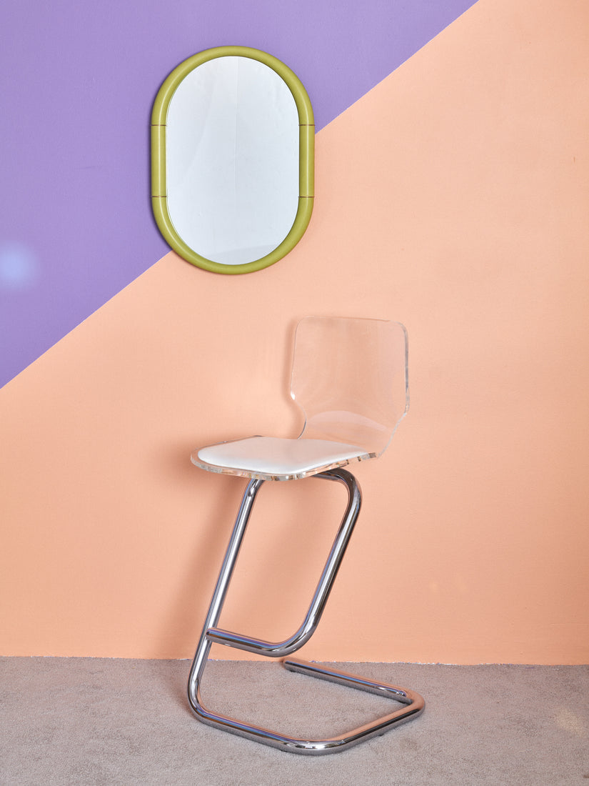 Ceramic Mirror by Entler hung on a peach and lavender wall above a vintage paperclip stool.