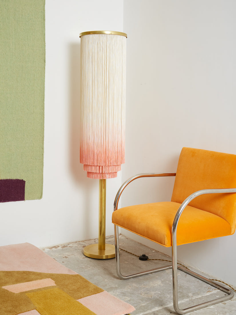 Barbara the Fringe Floor Lamp sits next to a tangerine BRNO chair.