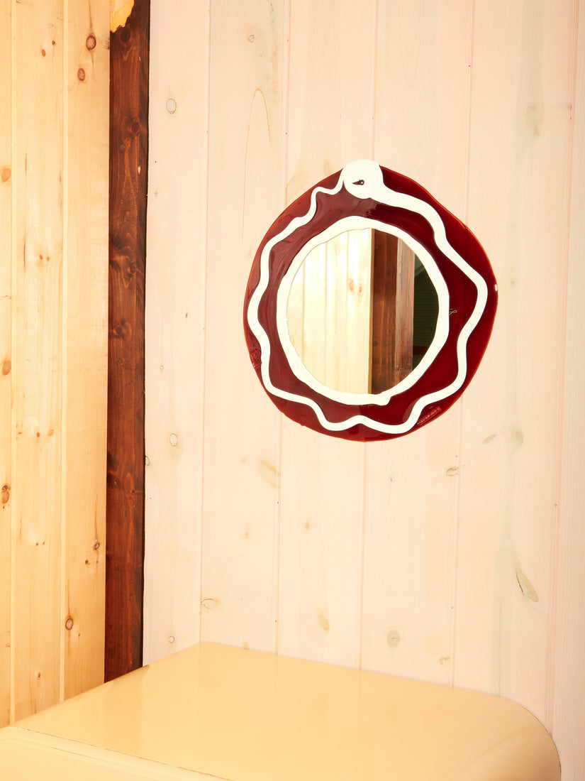 Brown and White Round Mirror by Gaetano Pesce for Fish Design hung on a wooden slat wall.
