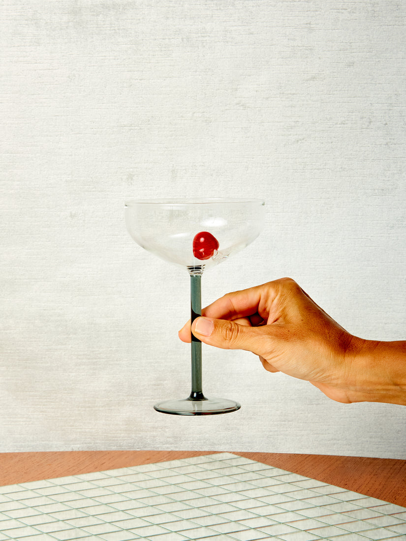 A hand holds a Manhattan Glass by Maison Balzac up by its stem.
