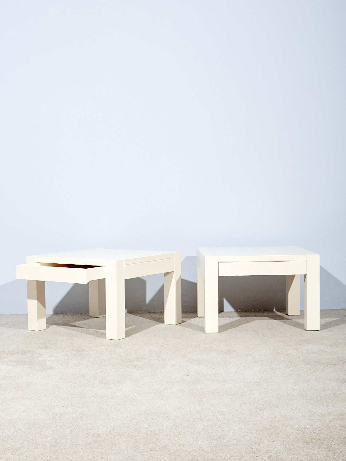 Pair of side tables by Gae Aulenti with hidden drawers. One drawer is slightly pulled out.