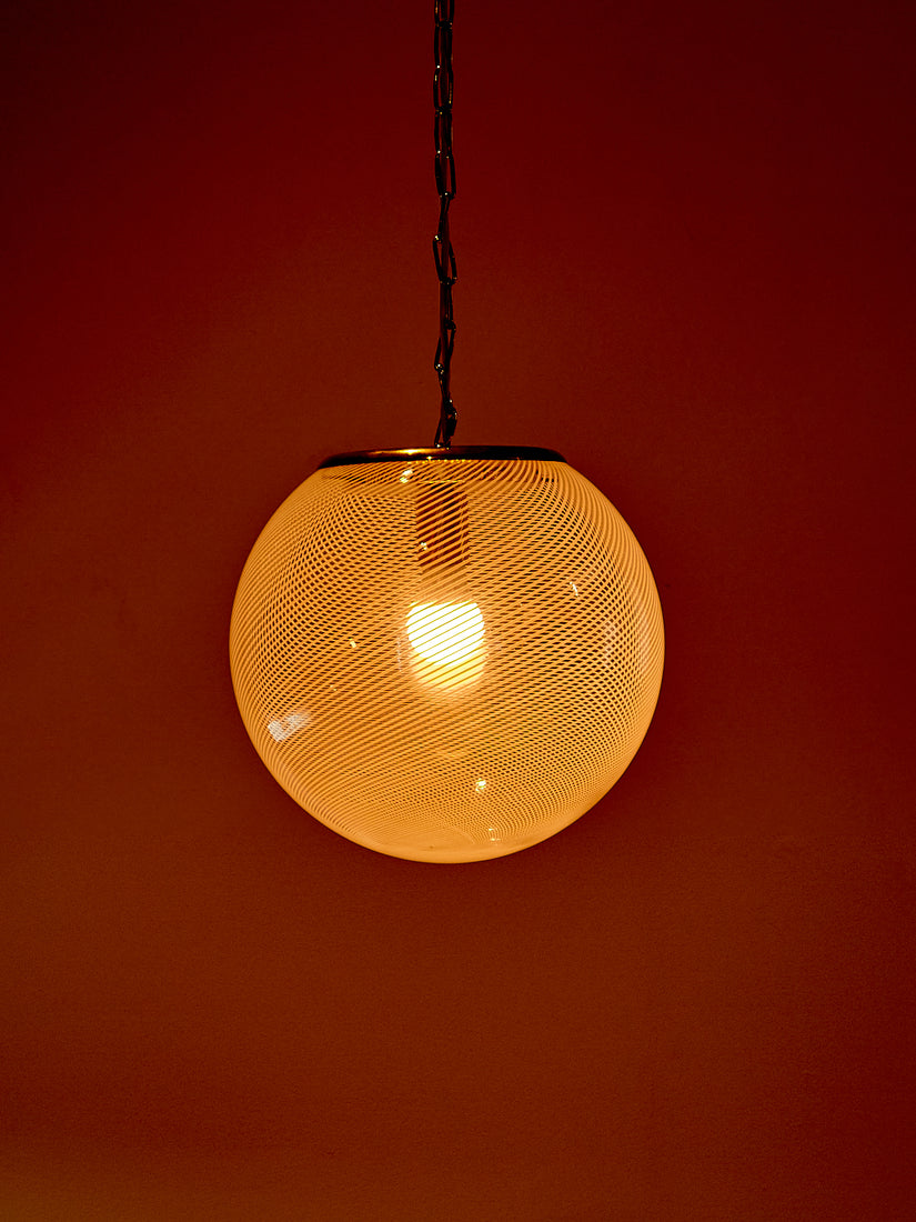 The Lattimo Glass Pendant Lamp glows in a dark space.