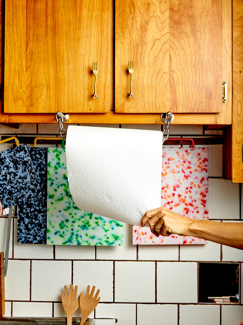 A hand pulls at the roll of paper towels on the Catena Paper Towel Holder.