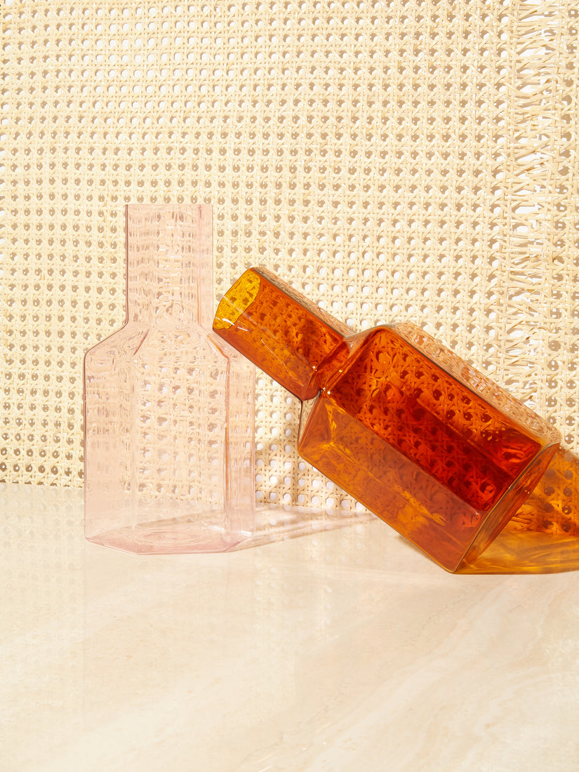 A pink Coucou Decanter by Maison Balzac with an amber version leaning on it.