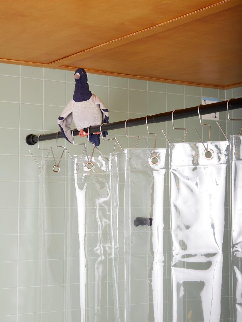 Quiet Town shower hooks on a black rod. A stuffed toy Pigeon sits on the rod.