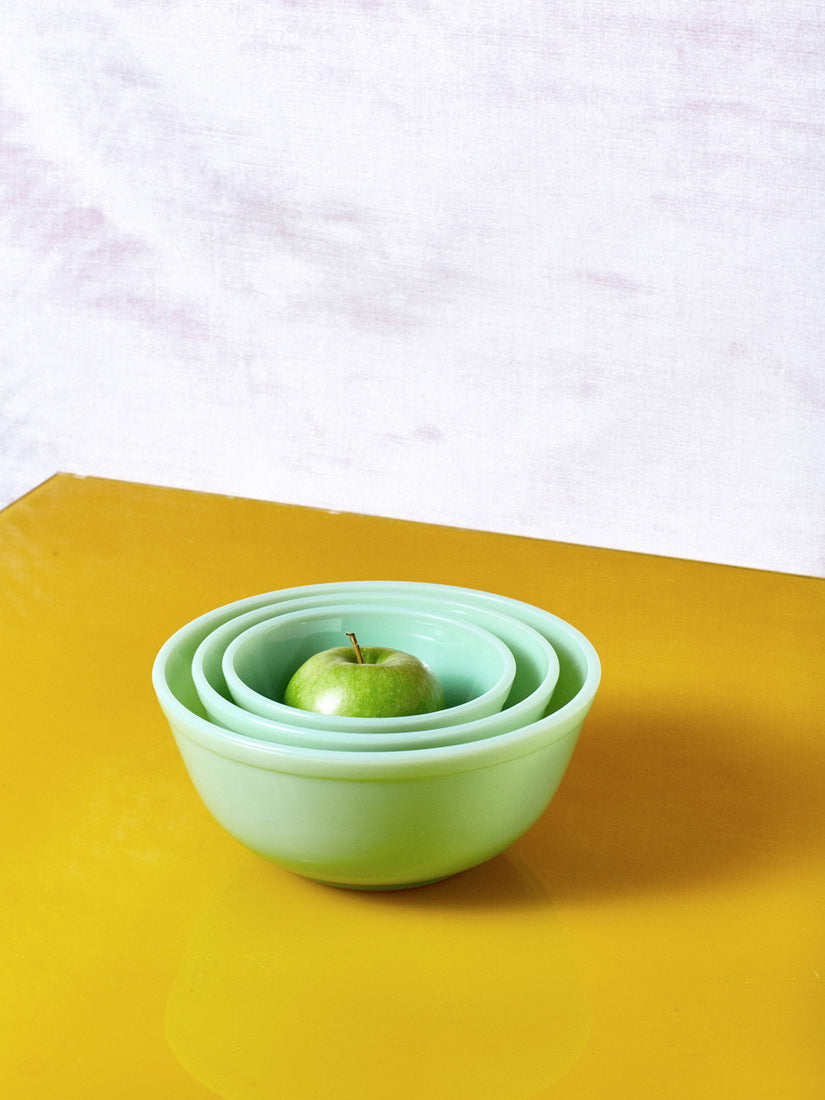 A set of 3 Jadeite Milk Glass Mixing Bowls by Mosser Glass with a green apple inside.