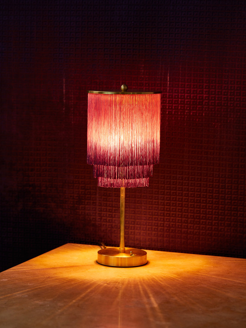 Purple Ombre Fringe Table Lamp by Huldra of Norway lit in a dark space.