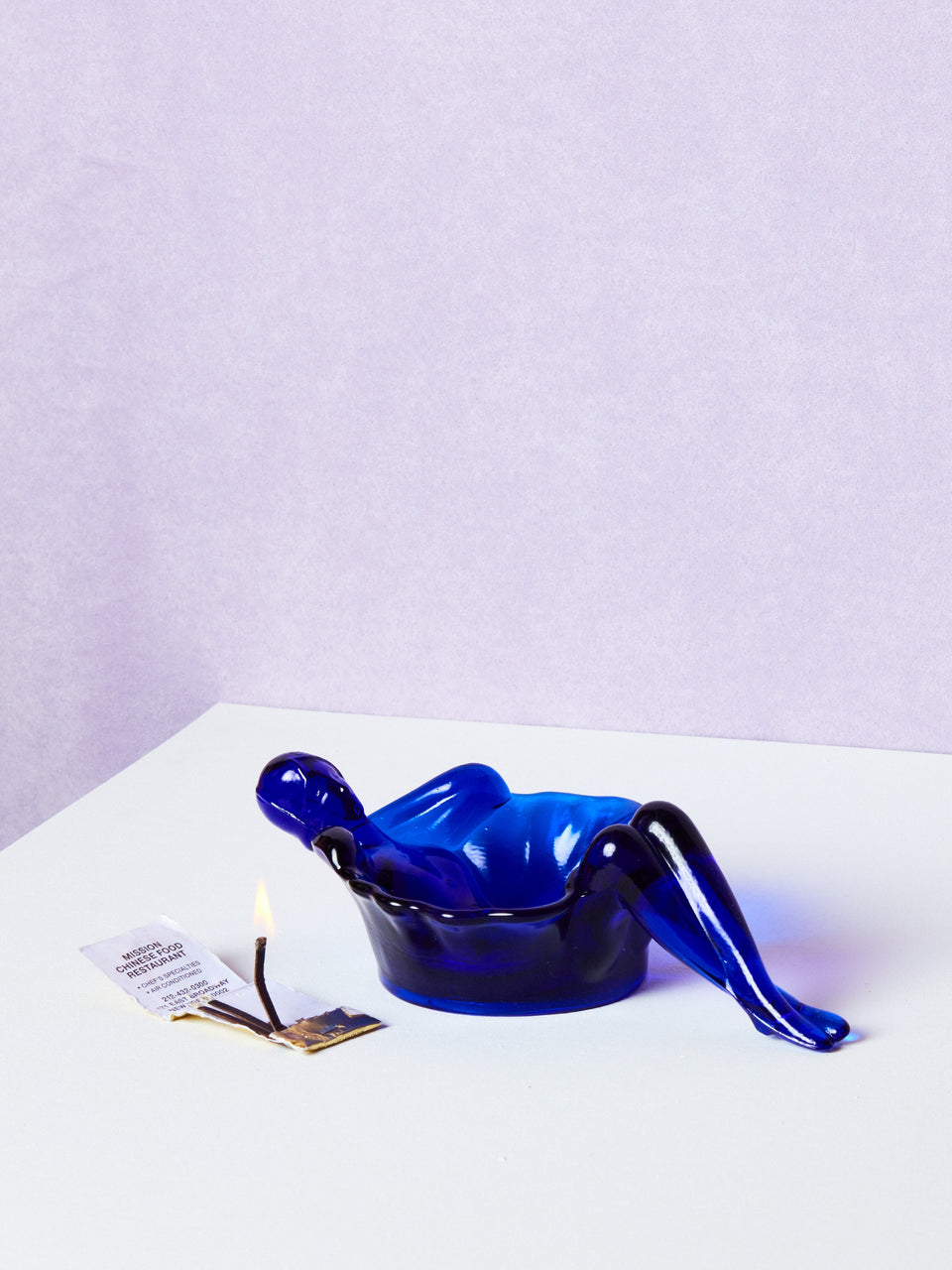 Blue plastic bathing lady dish on a white surface with a light purple background