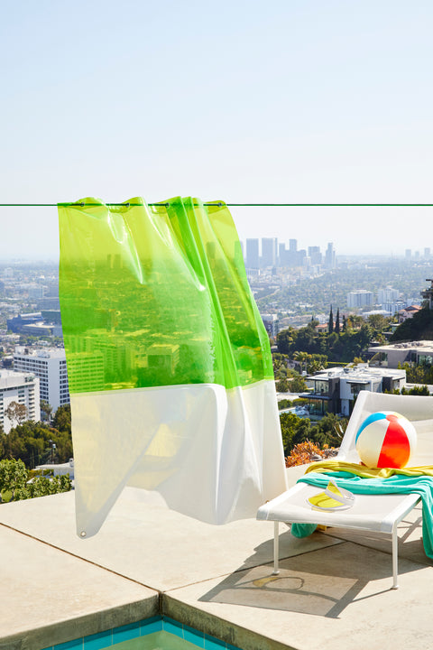 The Zinc Sun Shower Curtain hanging outside by a pool in front of a city scape.