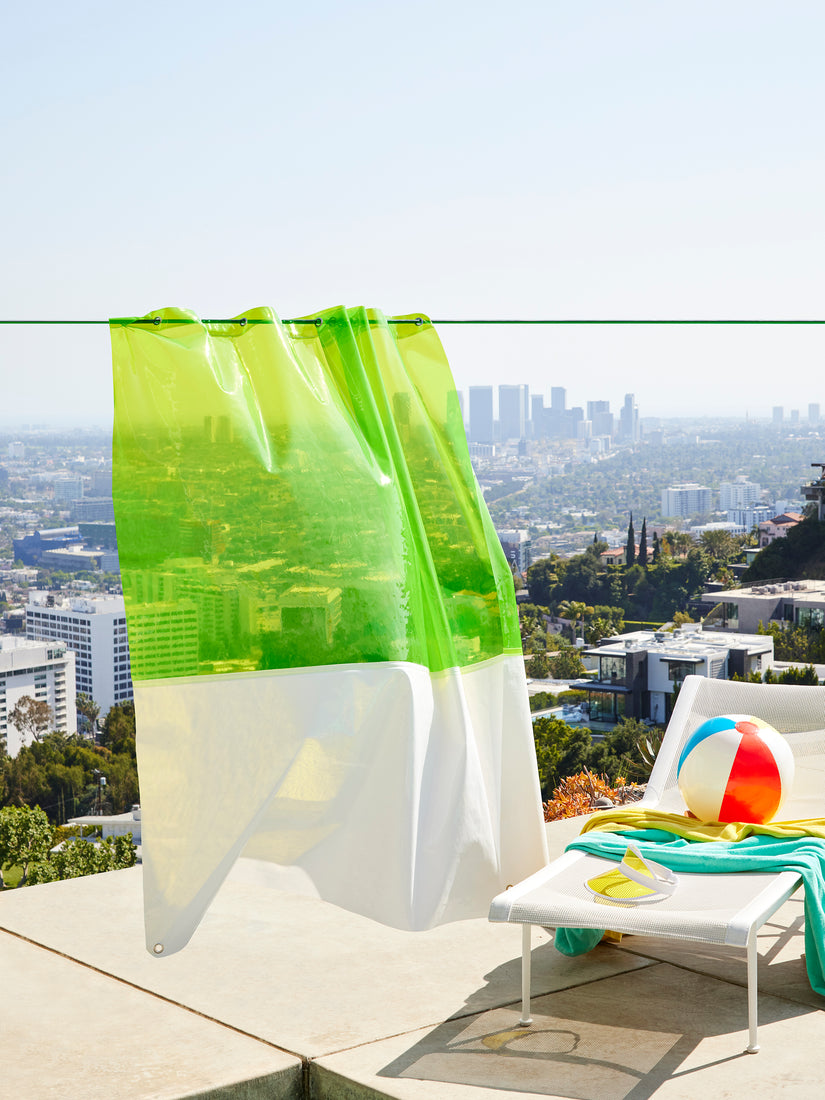 The Zinc Sun Shower Curtain hanging outside by a pool in front of a city scape.