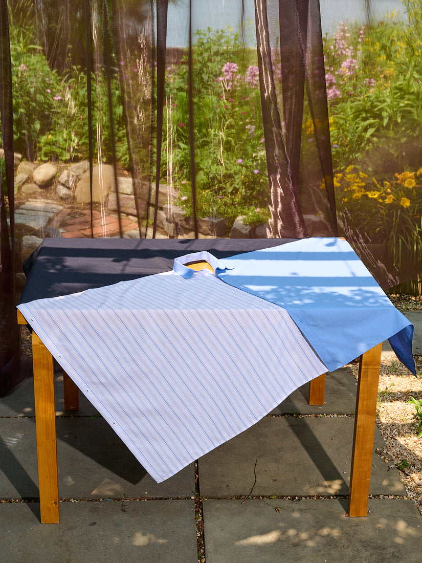 Shirt Tablecloth II by Gohar World draped diagonally over a square dining table in an outdoor patio.