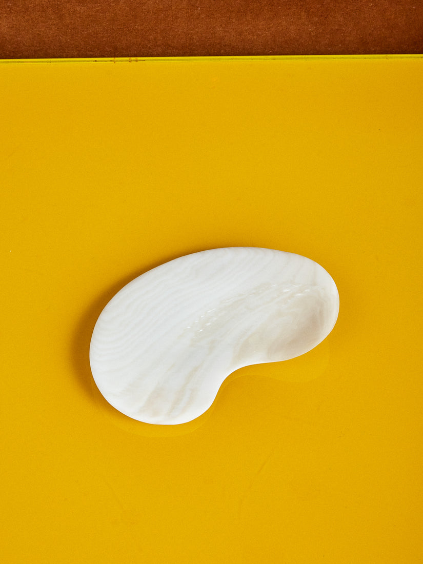 Bean Shaped Mother of Pearl Dish by Gohar World against a yellow surface.