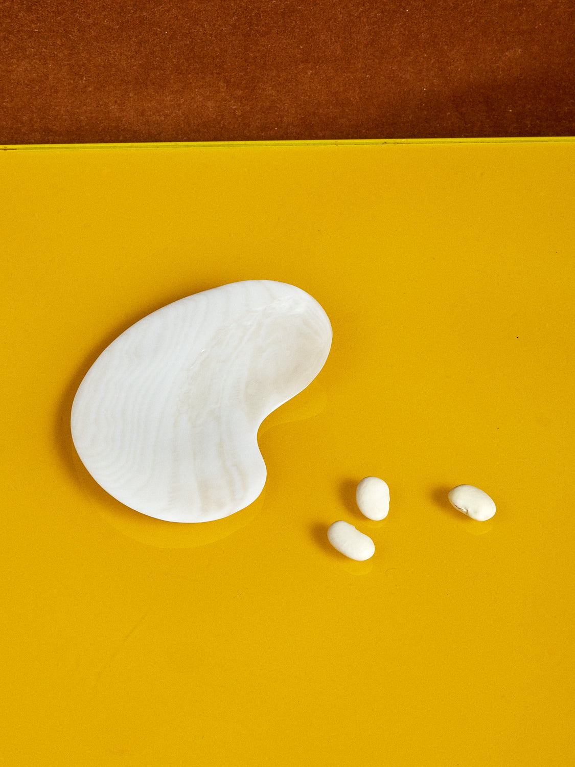 Mother of Pearl Bean Dish sits next to 3 white beans.