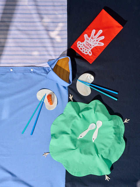 Tablescape including Gohar World Shirt Tablecloth, Cloth Napkin with Lace Hand, Mother of Pearl Bean Dish, chopsticks, Sea Creature Spoons, and Plate Cover in Green.