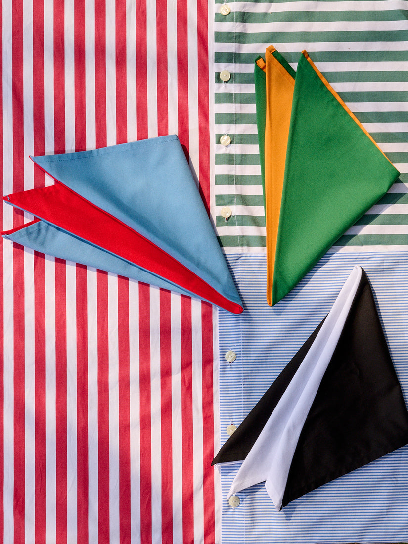 Colorblock Napkins by Gohar World in three colorways folded atop a Striped Table Cloth.