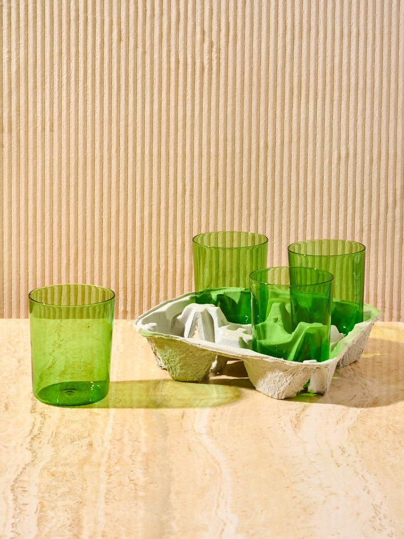 A green large goblet by Maison Balzac sits left of a drink carrier of 3 additional goblets.