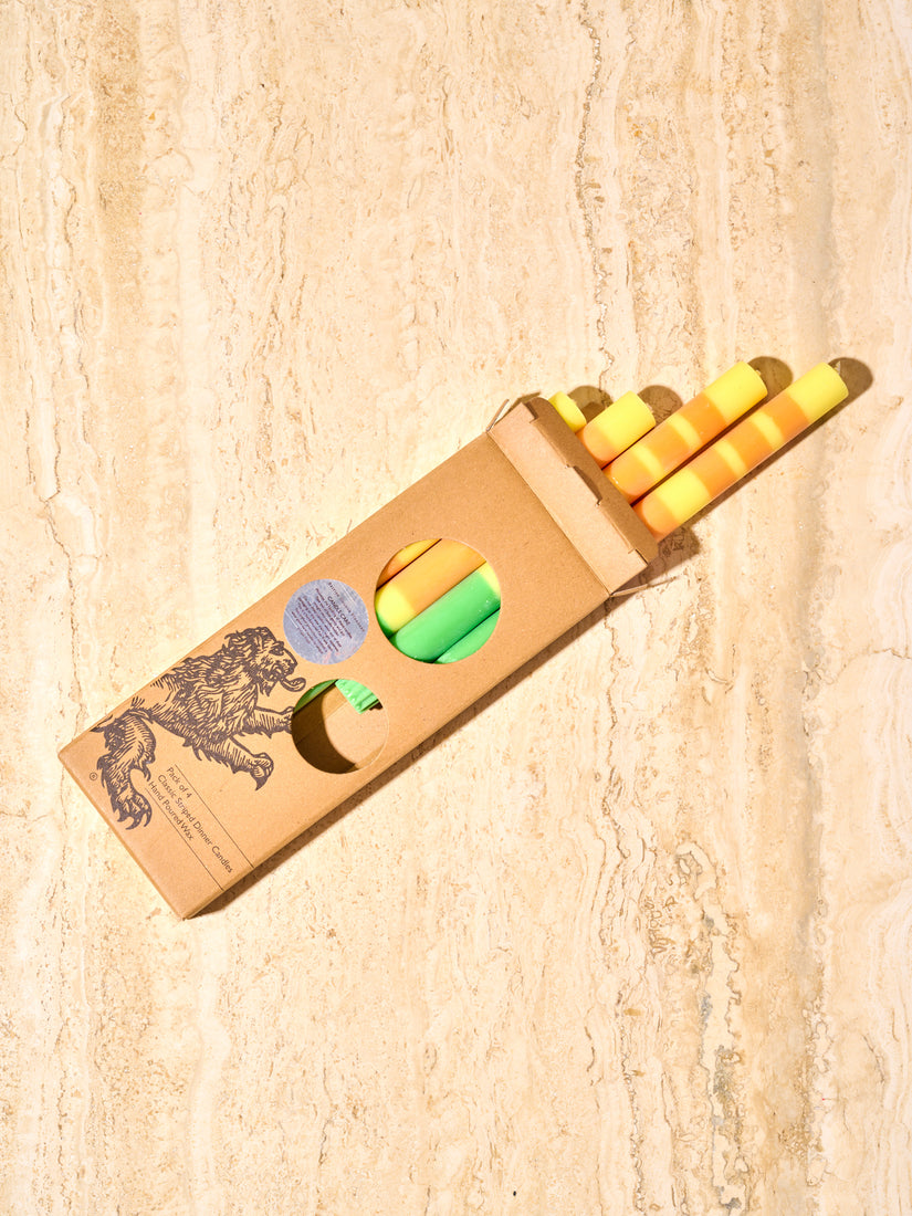 An open box of yellow, orange, and green taper candles by British Colour Standard.