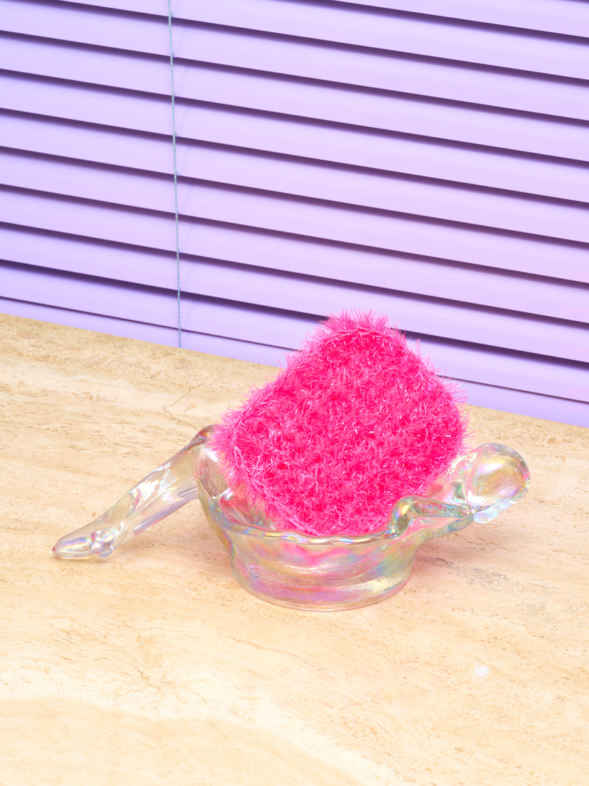 A hot pink sponge in an Iridescent Clear Bathing Lady dish by Mosser.