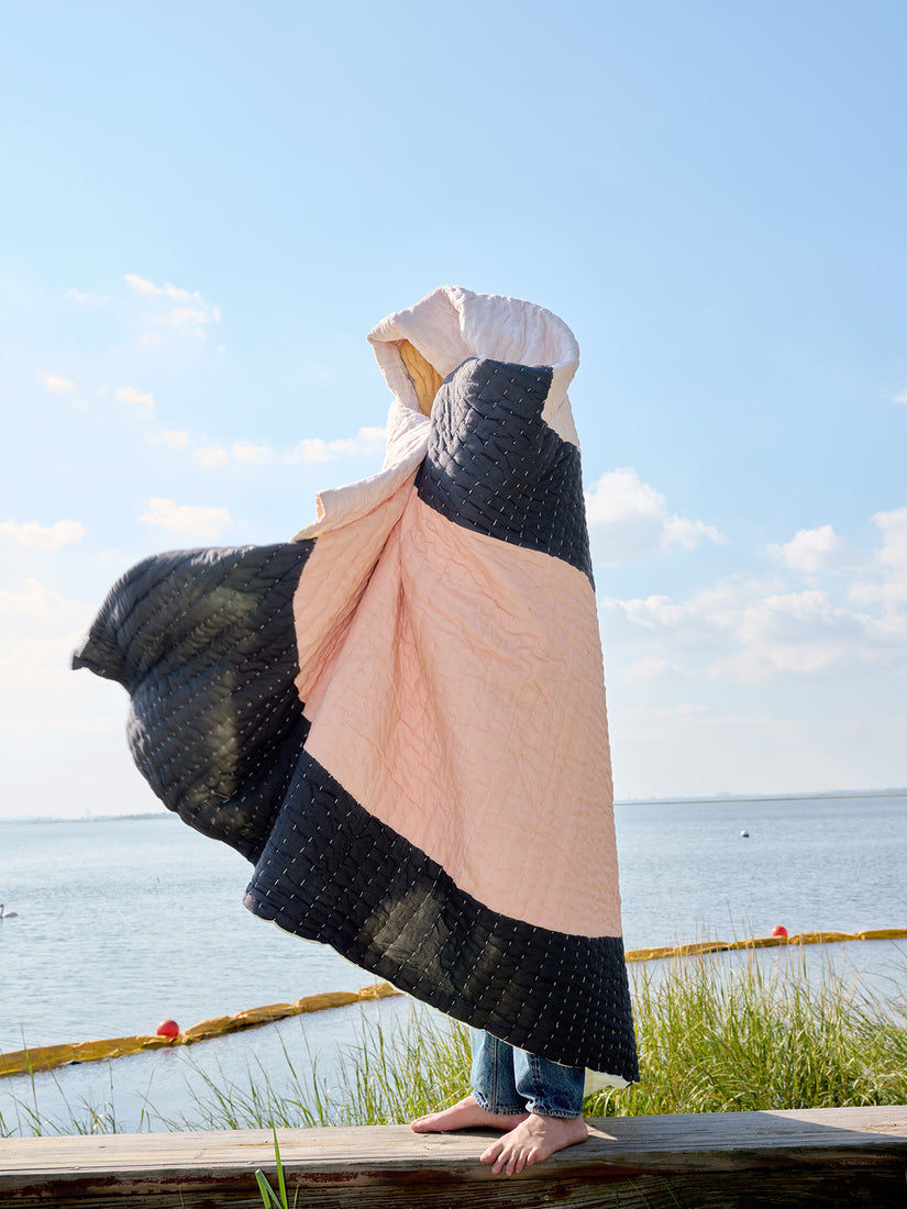 Someone stands on a dock wrapped up in a Summer is a Feeling Quilt by Cold Picnic.