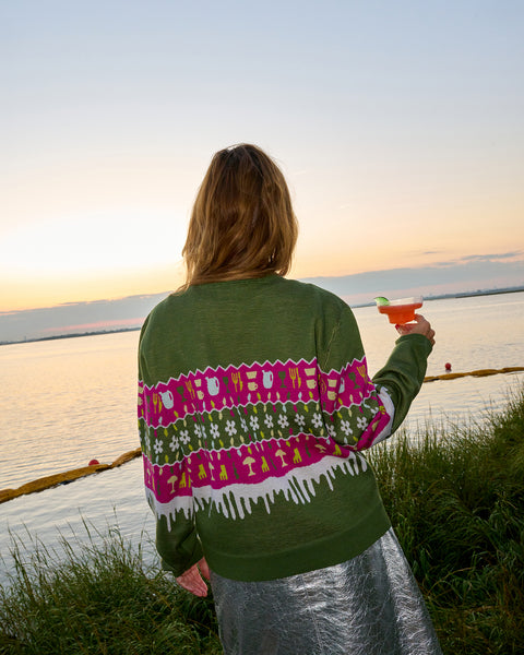 Someone stands holding a Margarita Glass, facing away, while wearing the Coming Soon x Sandy Liang holiday sweater.