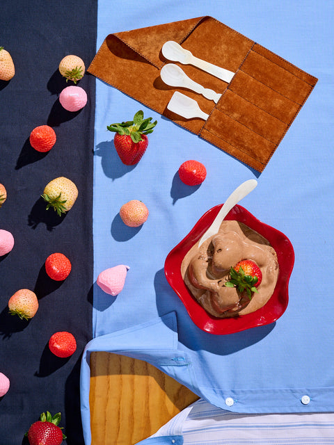 Strawberries, strawberry candles, and a big bowl of chocolate ice cream with a mother of pearl dessert spoon.